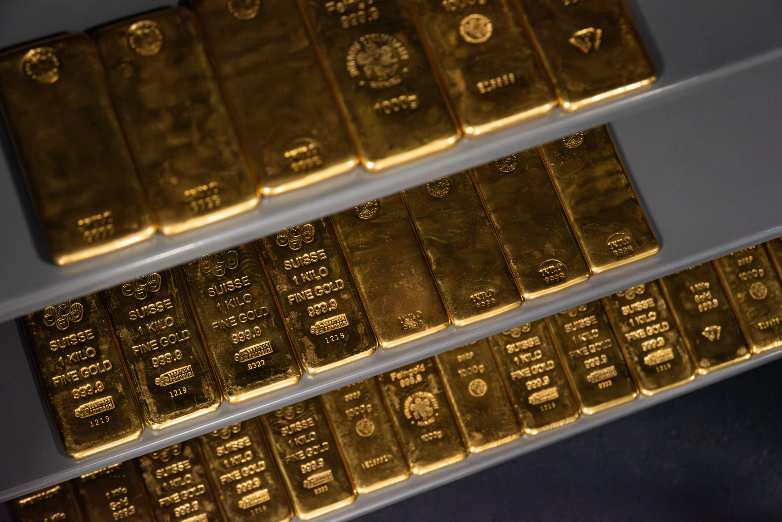 various 1 kilogram gold bars laying on racking within a tann safe shot at an angle